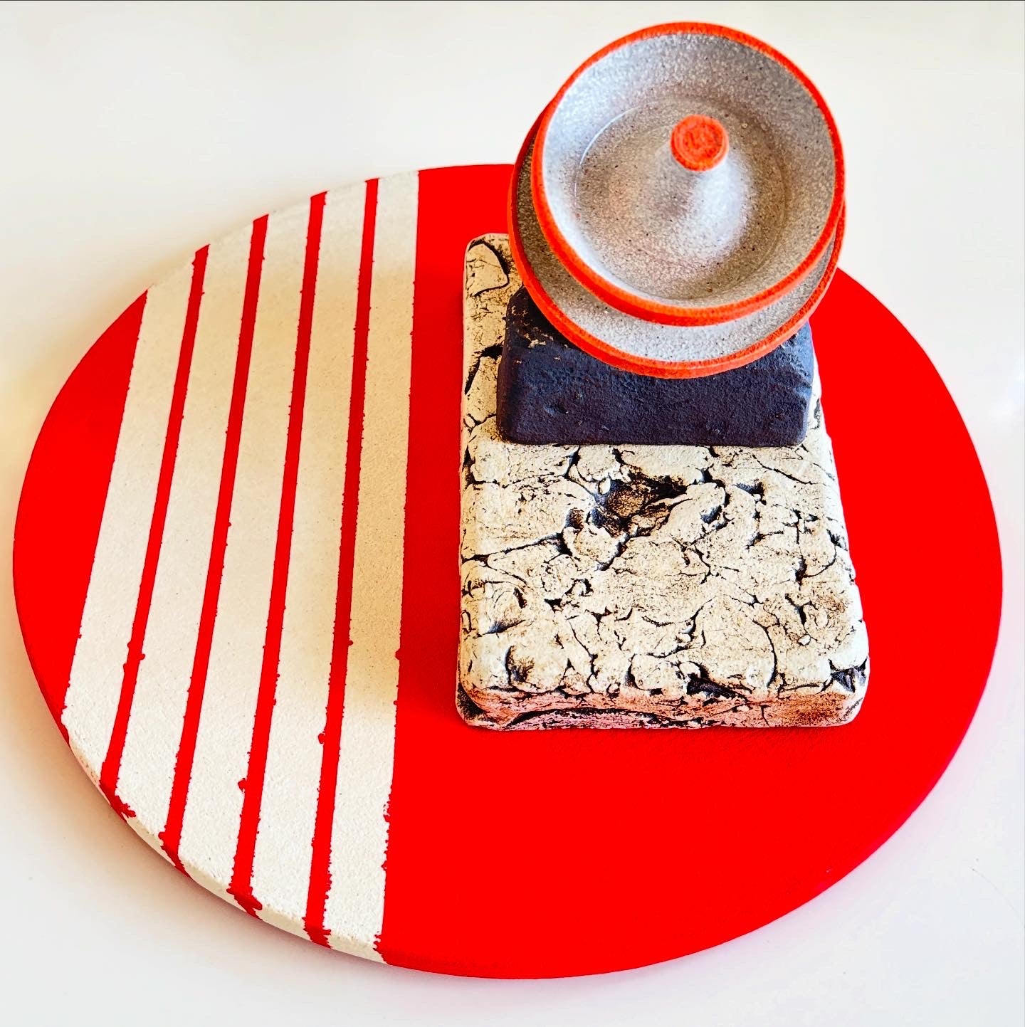 Decorative item with a red and white striped base and textured surface on a red circle background